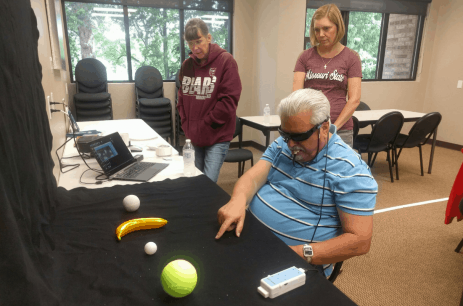 Blind Man, experimenting wicab tech, pointing at several objects, A plastic banana